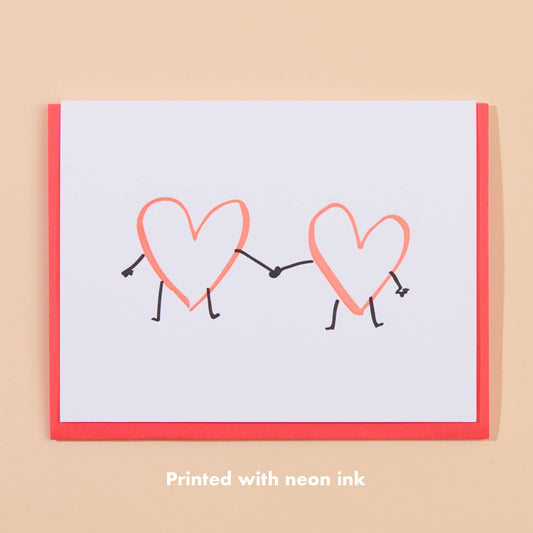 greeting card with two hearts holding hands