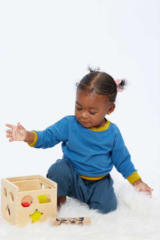 baby playing with blocks wearing a blue and yellow bamboo pullover