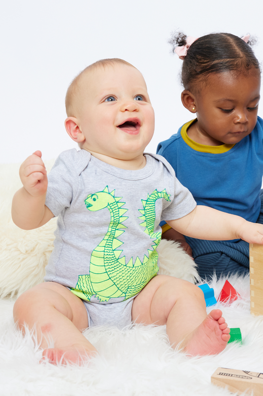 sitting baby wearing organic onesie with a cute dragon