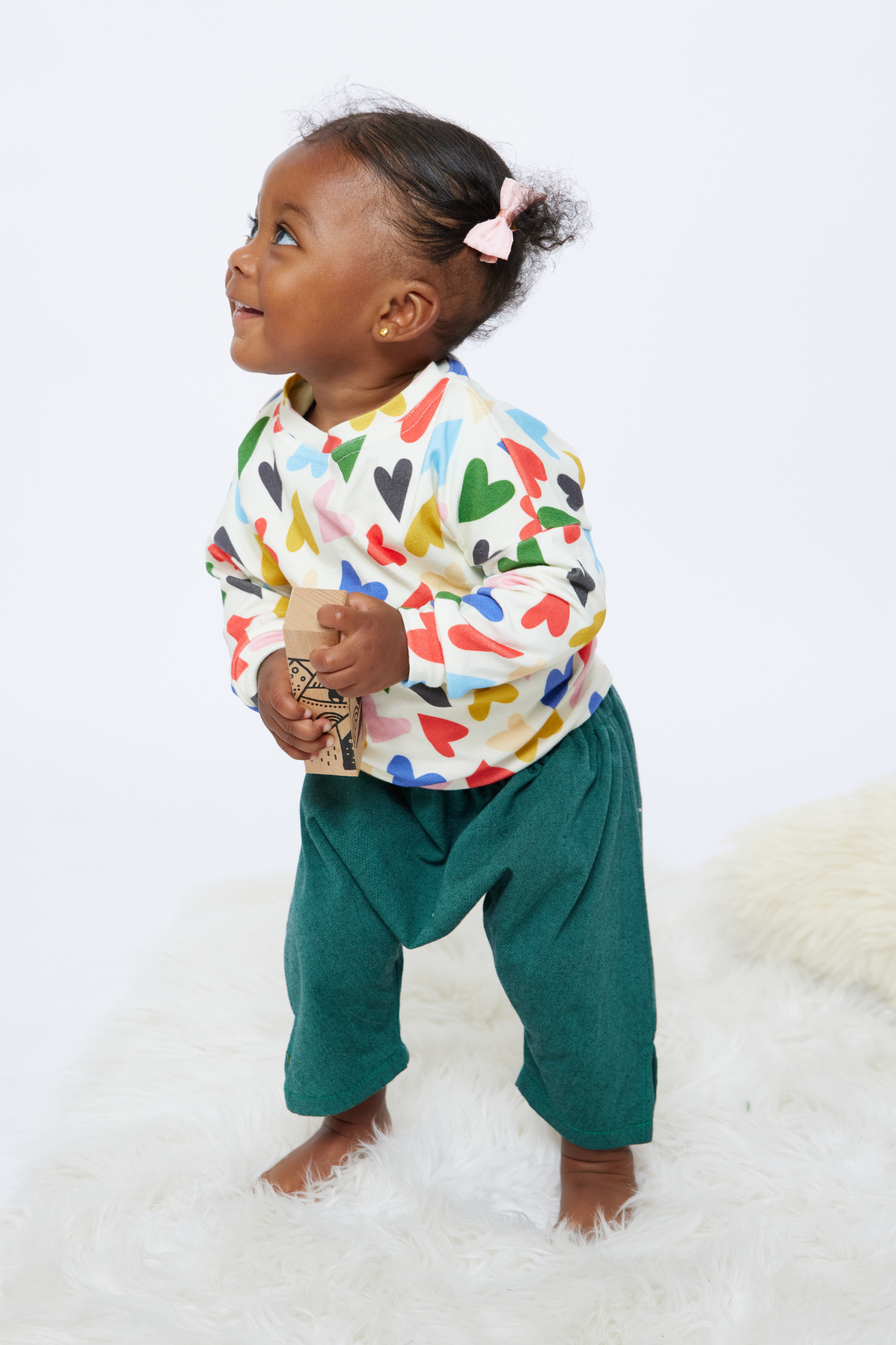 baby standing and smiling wearing colorful green baby pants